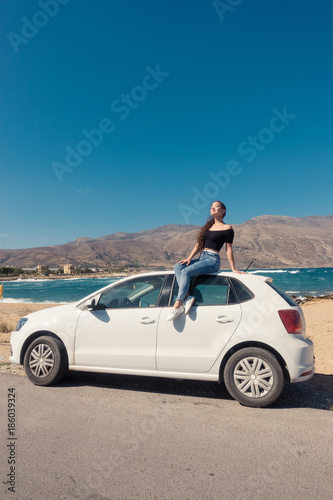 Happy pretty girl sit on the white car