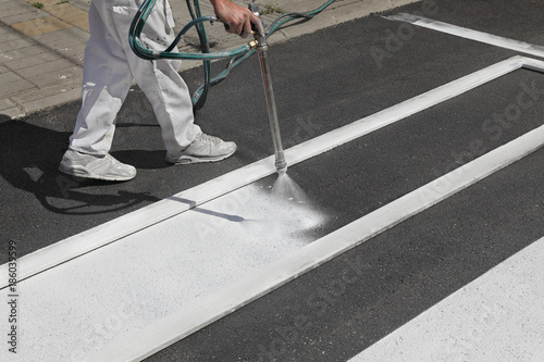 Worker spraying pedestrian crosswalk at a street