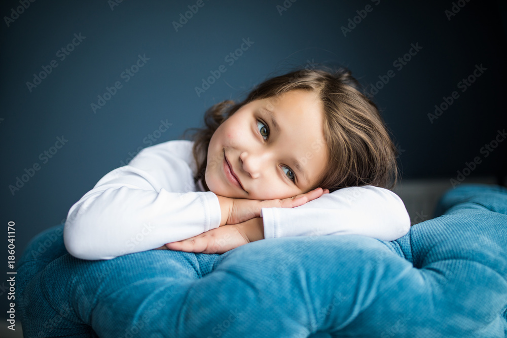 Portrait of happy pretty little girl lying and waiting on the chair at home