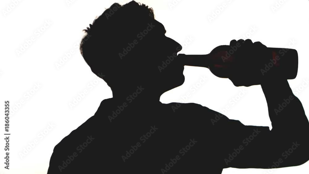 silhouette of young man drinks alcohol from a bottle isolated on white background