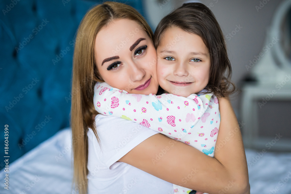 Mother and little daughter enjoy in bed at home and looking at the camera Mother and little daughter enjoy in bed at home and looking at the camera