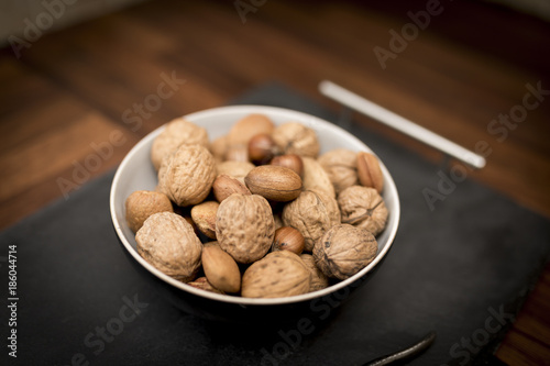 A bowl of mixed whole nuts in their shells including walnuts, hazelnuts, almonds and pecans with a short depth of field