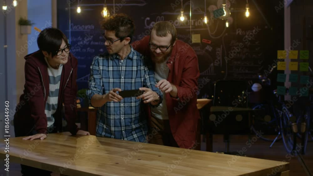 Great Concept For Augmented Reality Mock-up. Three Young Developers Look at Augmented Reality Through Smarthpone. They're Working on the New Virtual Reality Game. Great Concept For Augmented Reality Mock-up. Three Young Developers Look at Augmented Reality Through Smarthpone. They're Working on the New Virtual Reality Game.