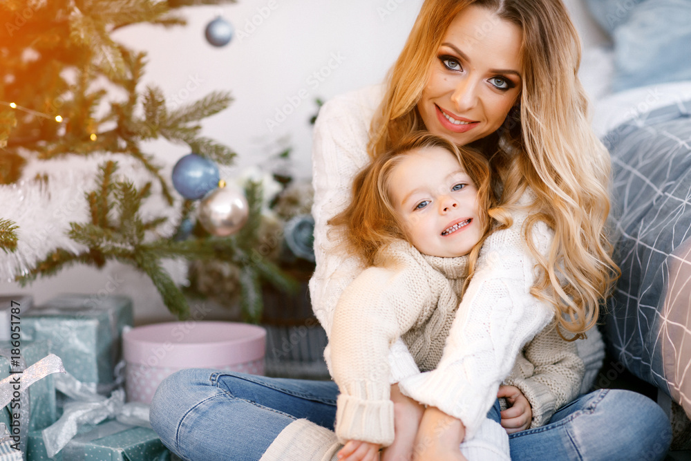 mother and daughter sitting by the christmas tree mother and daughter sitting by the christmas tree