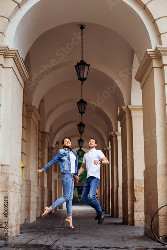 a couple in love jumping on the background of the building with arches and lanterns