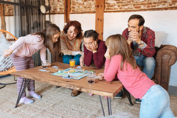 Happy family at home in the couch playing classic table games .