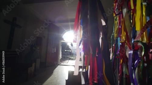 wide angle view through statue of Christ with colorful ribbon in sun light and flare inside Guadalupe church in ancient town San Cristobal de las Casas. photo