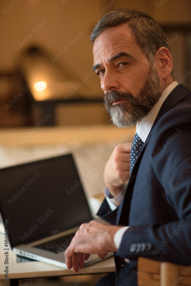 Senior older business man using a computer while sitting in a coffee shop Senior older business man using a computer while sitting in a coffee shop