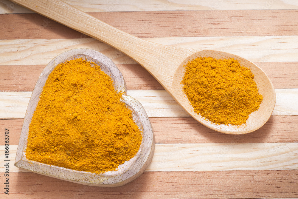 Turmeric powder with spoon on wood background (curcuma longa) Turmeric powder with spoon on wood background (curcuma longa)