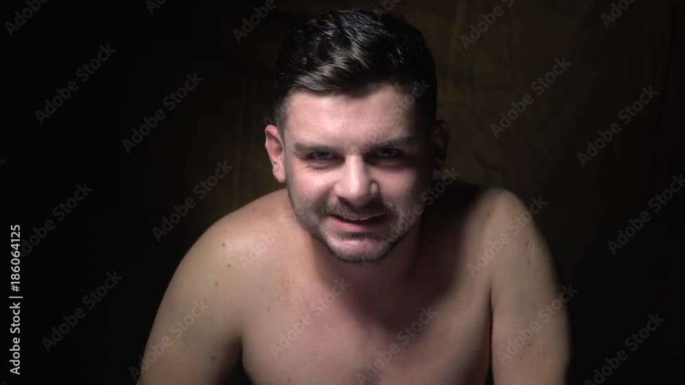 A bearded man stares intently into the camera and bites his lip A bearded man stares intently into the camera and bites his lip