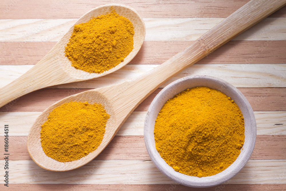 Turmeric powder with spoon on wood background (curcuma longa) Turmeric powder with spoon on wood background (curcuma longa)