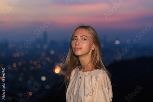 Portrait of young attractive caucasian woman during night with city background.