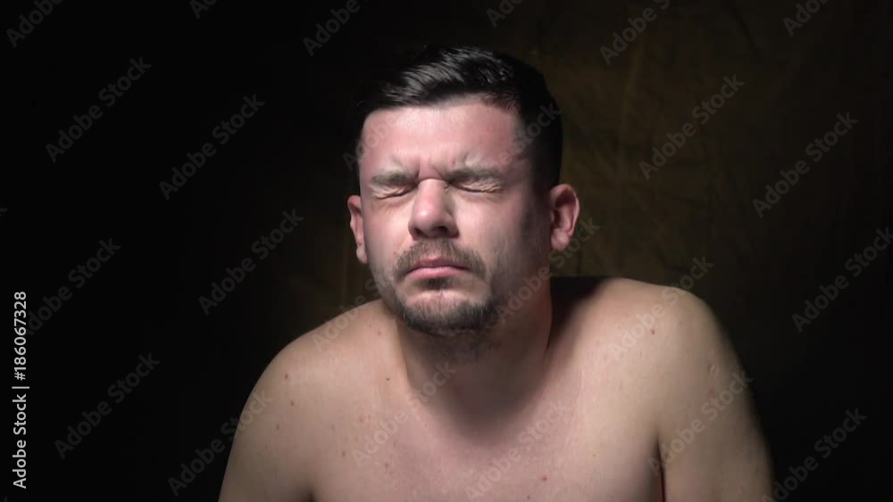 A bearded man suffers from a headache and massages the temple A bearded man suffers from a headache and massages the temple