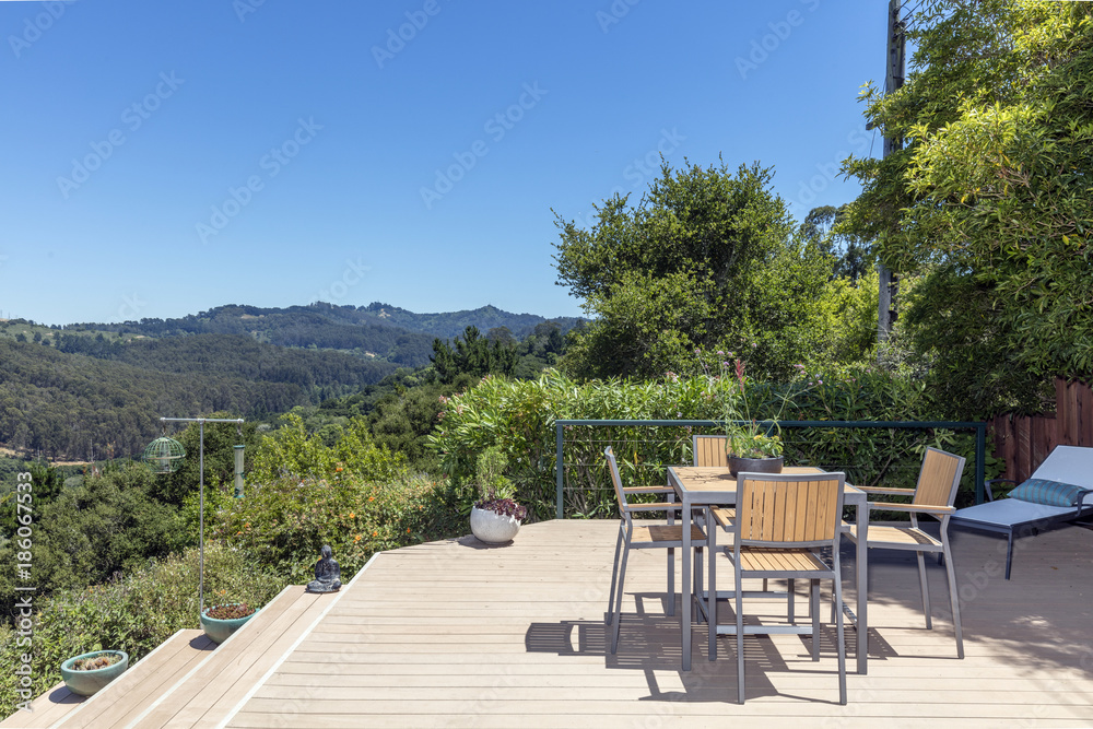 Amazing patio / wooden deck with outdoor furniture and mountain view at daytime.