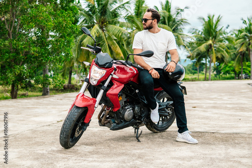 Rider sitting on his motorbike on palm background