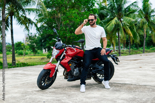 Quadro su tela Biker standing near his motocycle