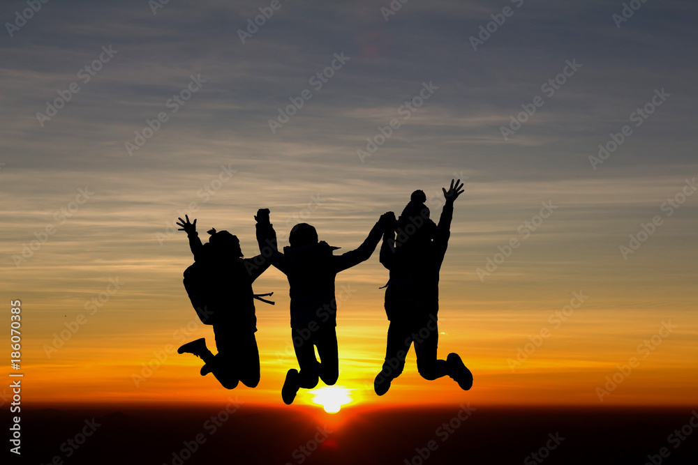 Happy three young girls with backpack jumping at sunrise or sunset time.