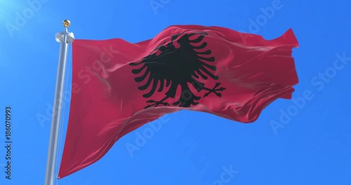 Albania flag waving at wind with blue sky, loop photo