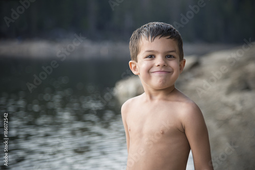 Fototapeta Naklejka Na Ścianę i Meble -  Smiling, shirtless, adorable little boy after swimming at mountain lake