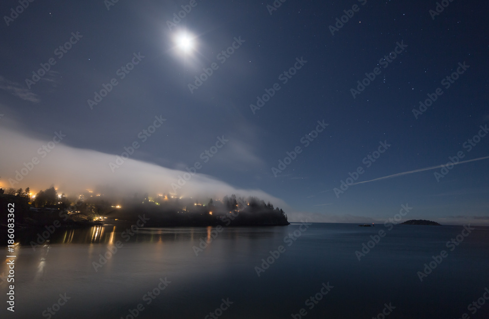 Fog covering the land on a starry night with moon lit