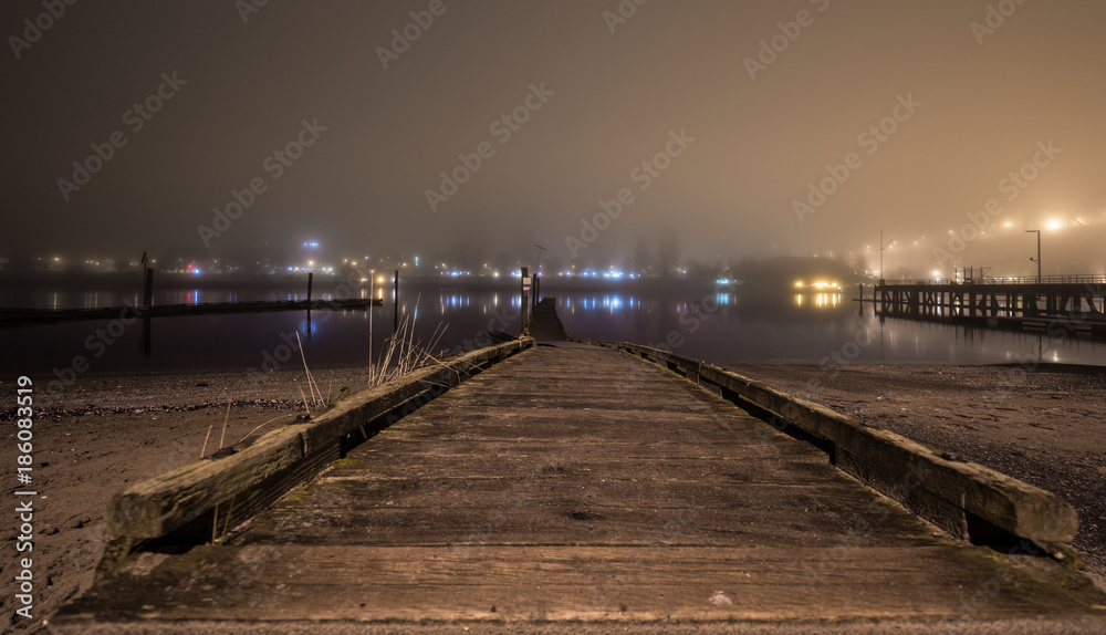 Long dock by the ocean on a foggy night