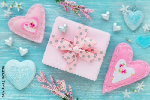 Valentine's Day concept with twrapped gift box and many different hearts on turquoise color wooden background