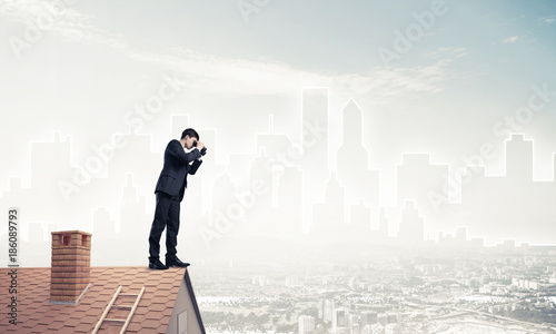 Businessman standing on roof and looking in binoculars. Mixed me © adam121