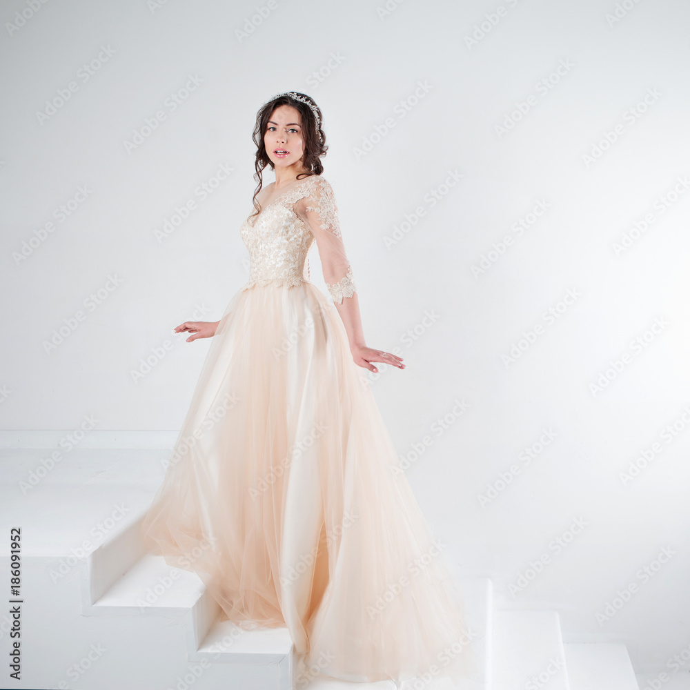 Portrait of a beautiful girl in a wedding dress. Bride in a luxurious dress standing on the stairs, climb up