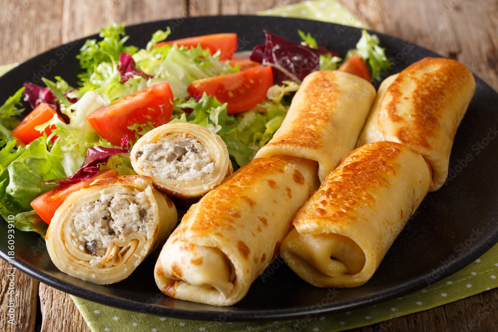crepes rolls with chicken, cheese and mushrooms close-up and salad of fresh vegetables. horizontal crepes rolls with chicken, cheese and mushrooms close-up and salad of fresh vegetables. horizontal
