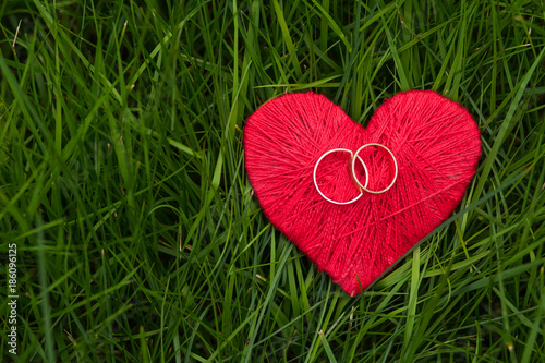 love heart and two golden rings on green grass background .card with love. emotions and feelings concept. Selective focus. Copy space