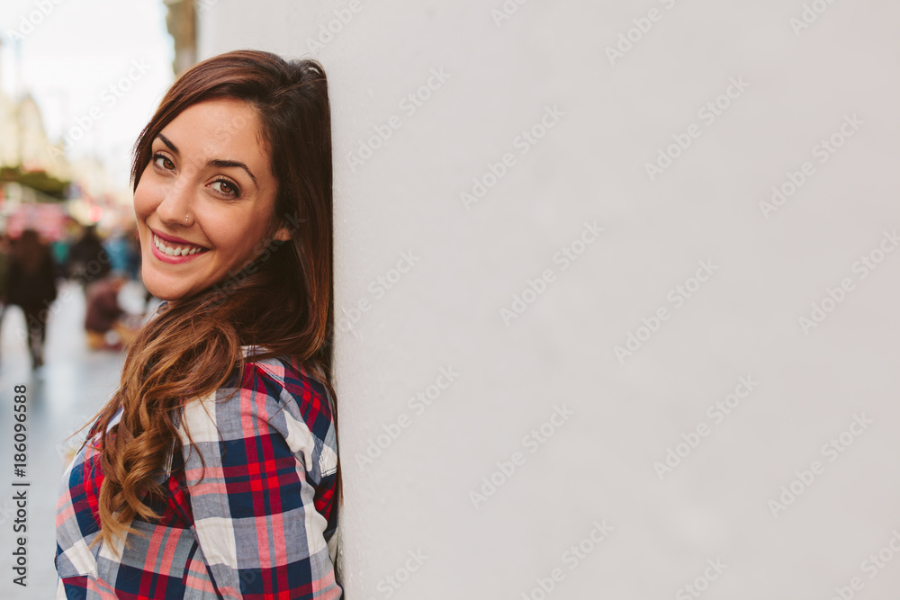 Young Girl Smiling while Leaning Against a White Wall Young Girl Smiling while Leaning Against a White Wall