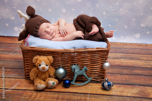 newborn baby in a deer suit under the Christmas tree