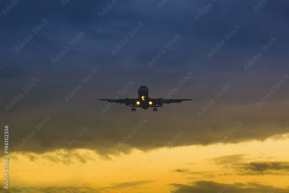 The plane takes off on the background of sunset and flies at dusk
