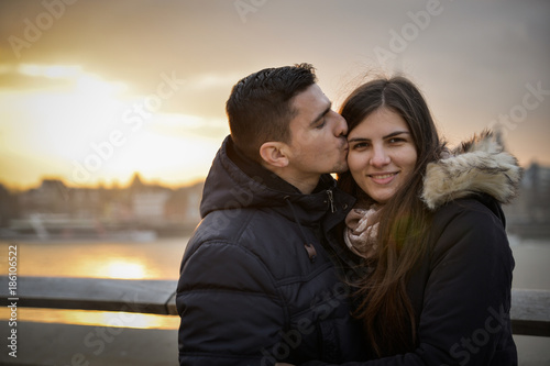 Romantic couple sitting on a bridge at sunset