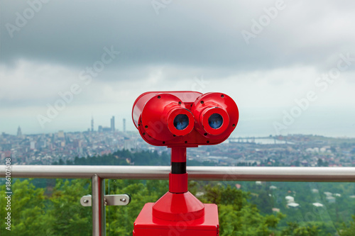 Coin operated red binocular towerview on observation deck with view on the sea and city photo