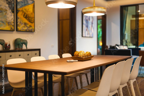 Luxury interior design in living room of pool villas. Airy and bright space with high raised ceiling and wooden dining table