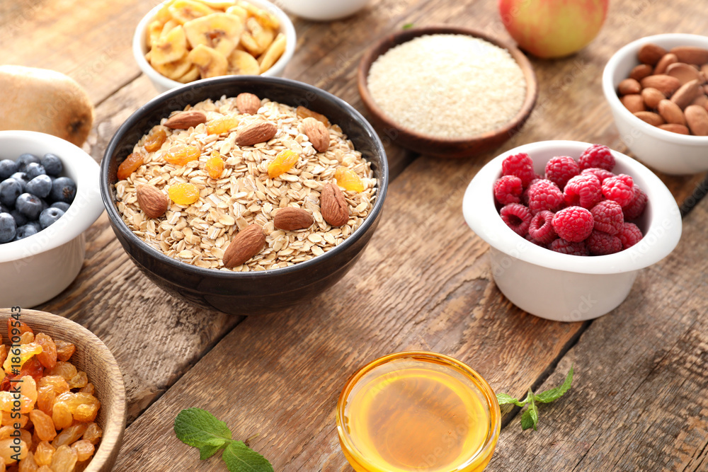 Oatmeal flakes and many different toppings on wooden background Oatmeal flakes and many different toppings on wooden background