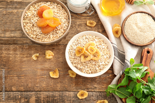 Composition with oatmeal flakes and toppings on wooden background