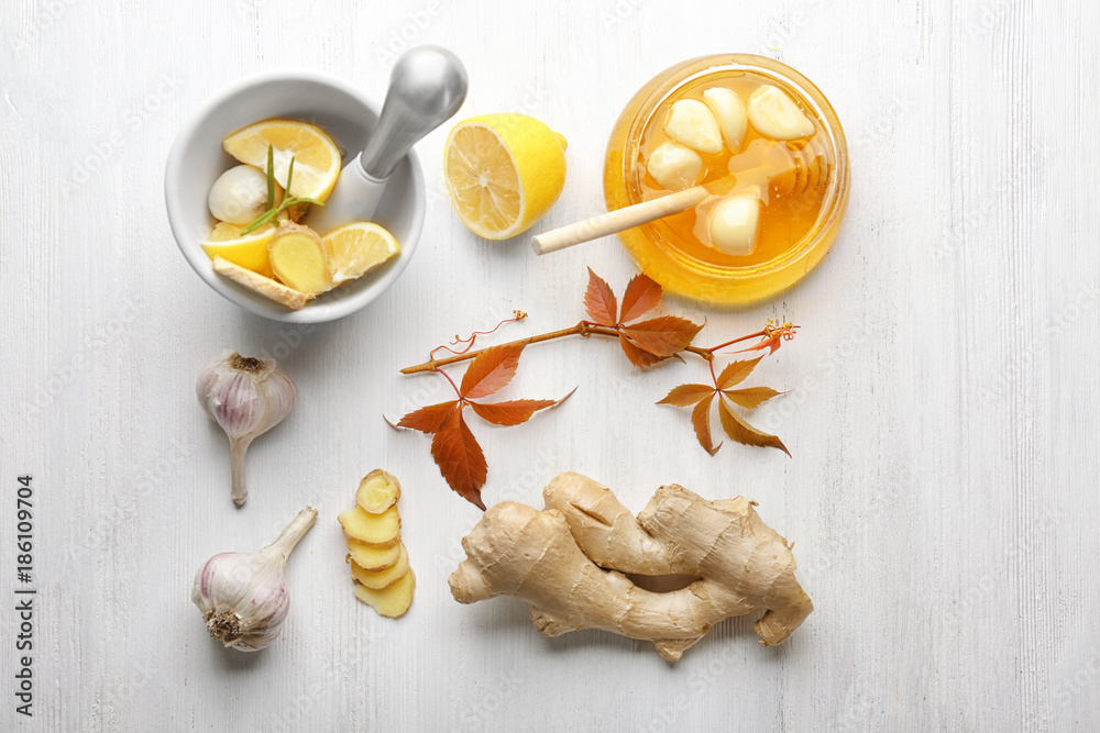 Composition with honey and garlic as natural cold remedies on white wooden background, top view