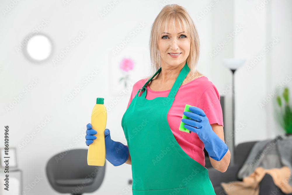 Mature woman with bottle of detergent and sponge at home Mature woman with bottle of detergent and sponge at home