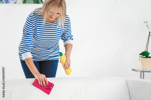 Mature woman cleaning sofa ...