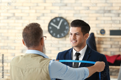 Senior tailor taking client...