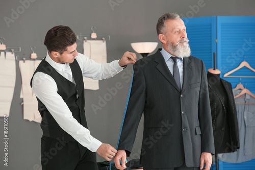 Tailor taking client's meas...