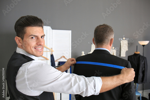 Tailor taking client's meas...