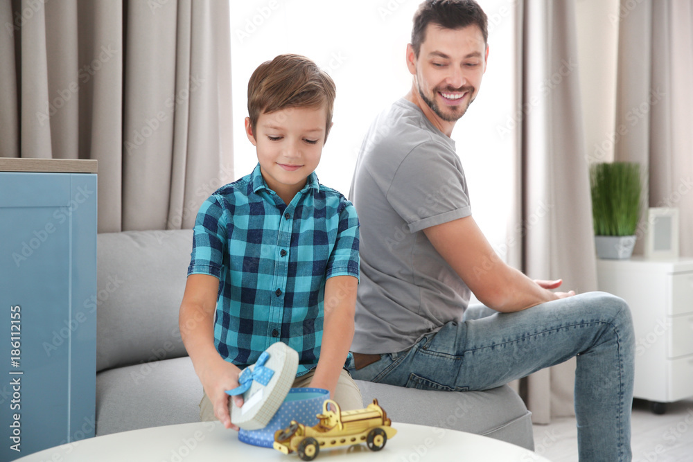 Cute little boy with gift box and father at home Cute little boy with gift box and father at home