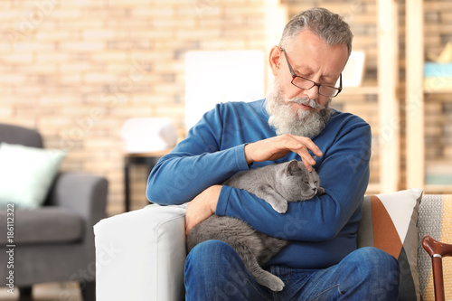 Schilderij op canvas Senior man holding cute cat at home