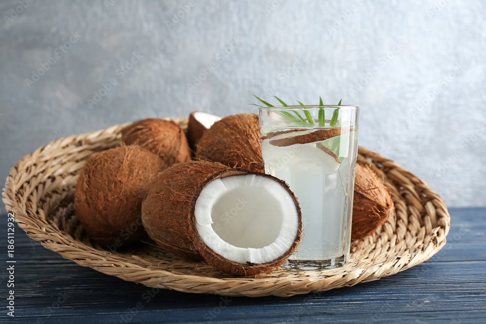 Glass of coconut water with nuts on wicker tray