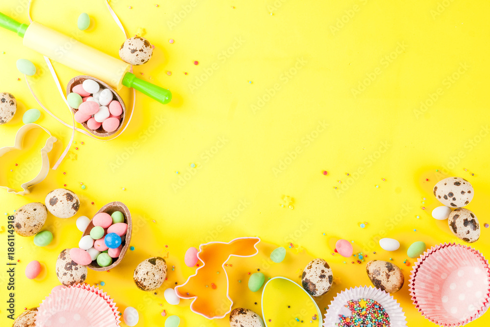 Sweet baking concept for Easter, cooking background with baking - with a rolling pin, whisk for whipping, cookie cutters, quail eggs, sugar sprinkling. Bright yellow background, top view copy space