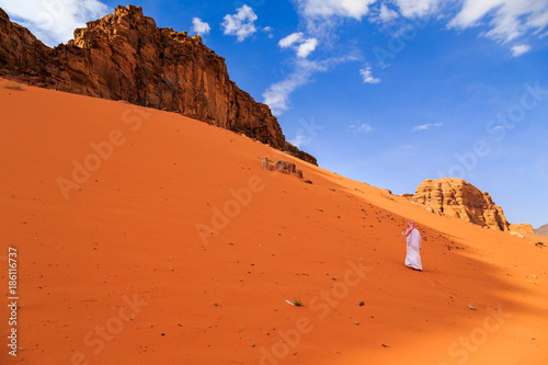 Arab person walking on a sand dune in the Wadi rum desert in Jordan at early-morning