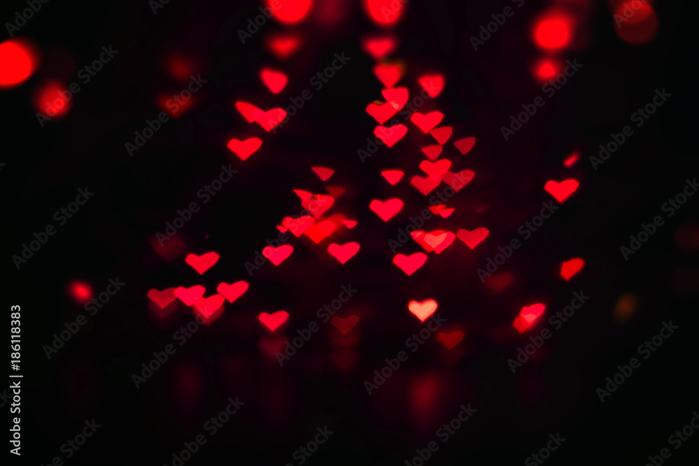Fototapeta Valentine's background with many little luminous red hearts on black, bokeh effect.